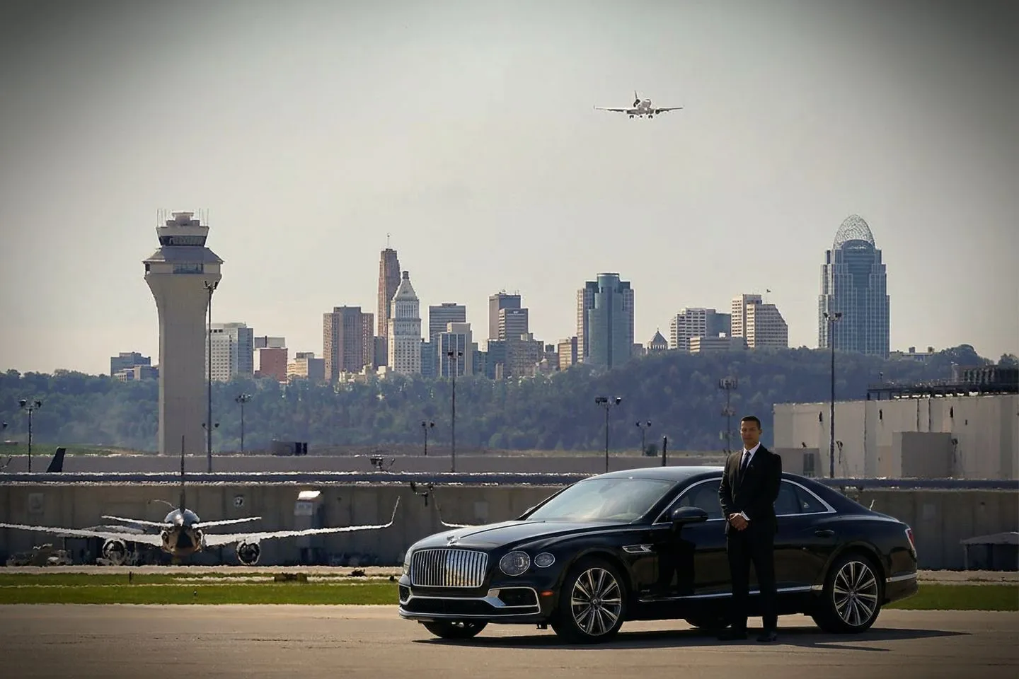 Kentucky, KY Car Service chauffeur standing beside black car at hotel entrance for pickup
