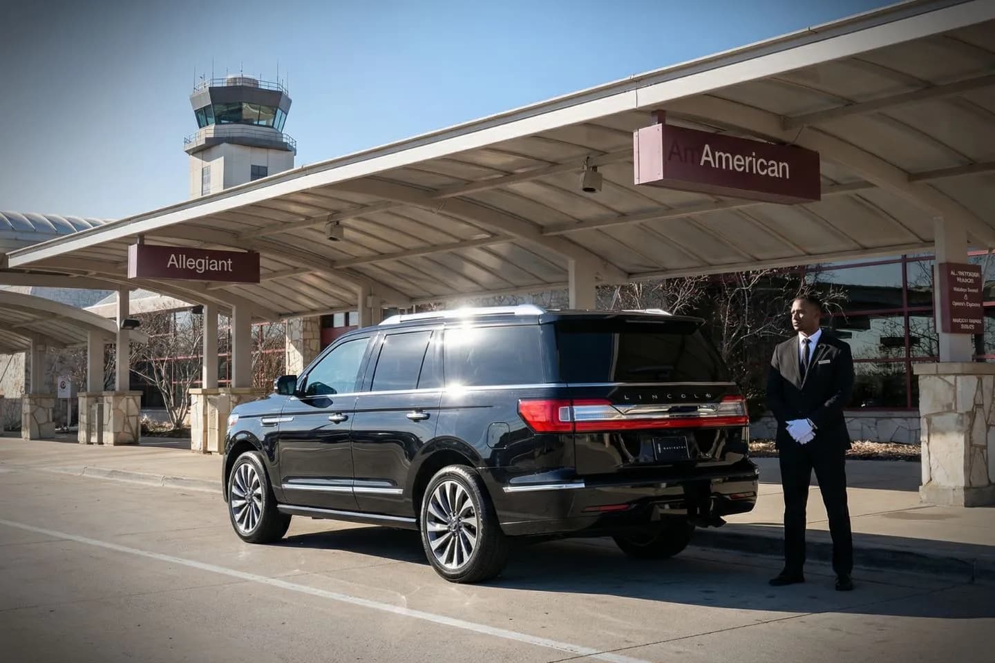 Black luxury sedan parked outside Bloomington Normal Regional Airport terminal