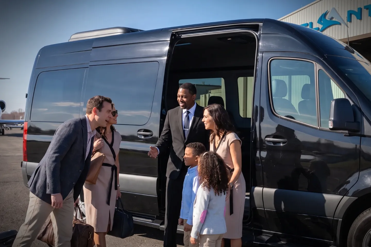 Corporate travelers walking from a jet to a black car at Oxford Airport