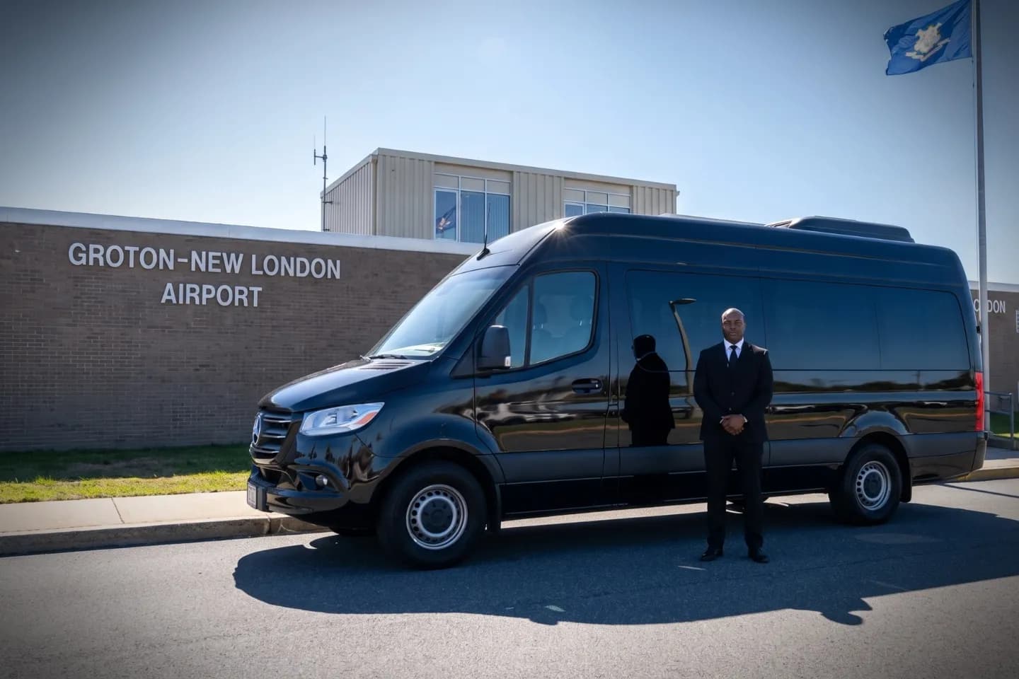 Black limousine parked outside the Groton New London Airport terminal on a sunny day