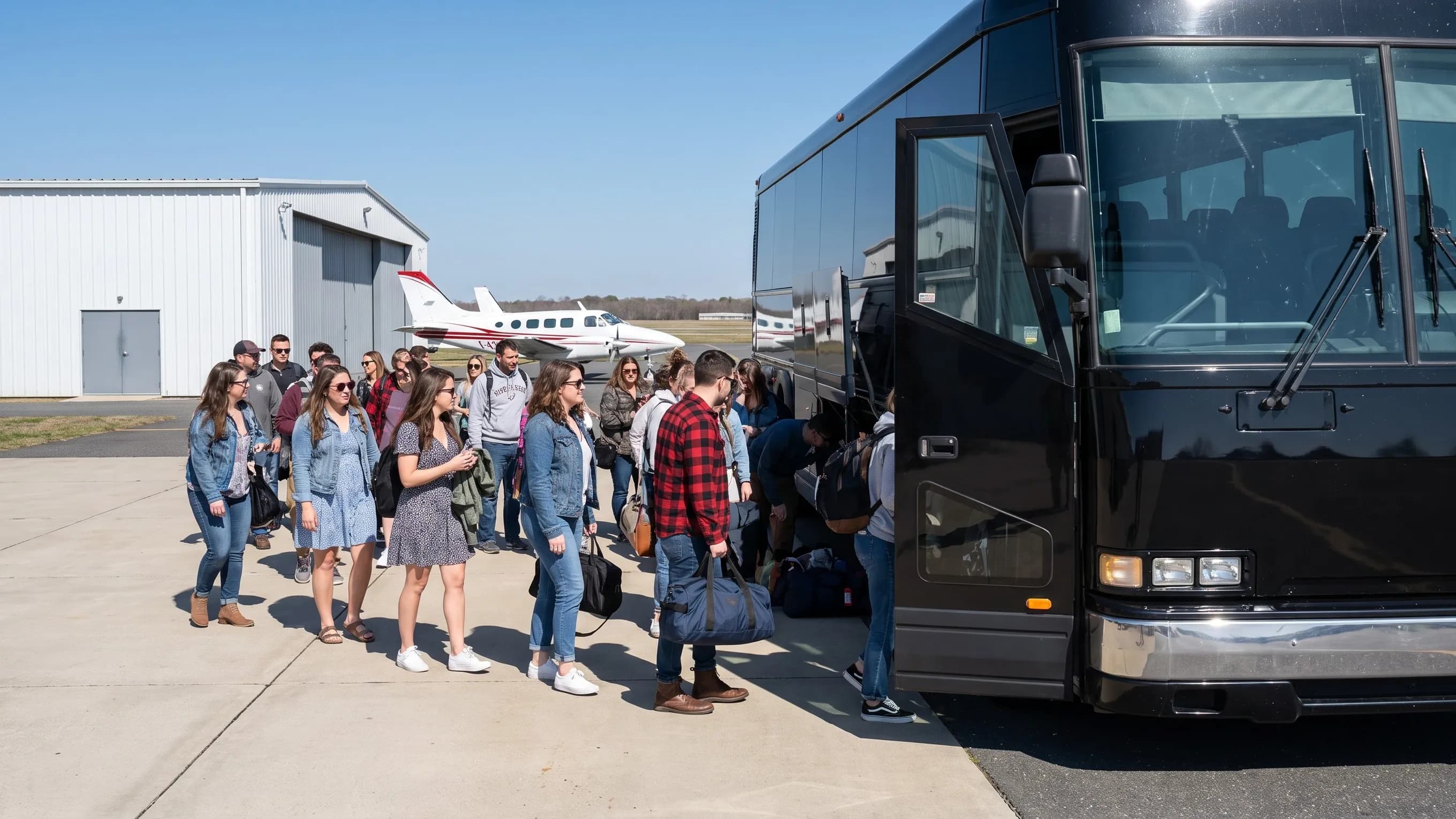 Passengers boarding a coach near light aircraft at LLY airport