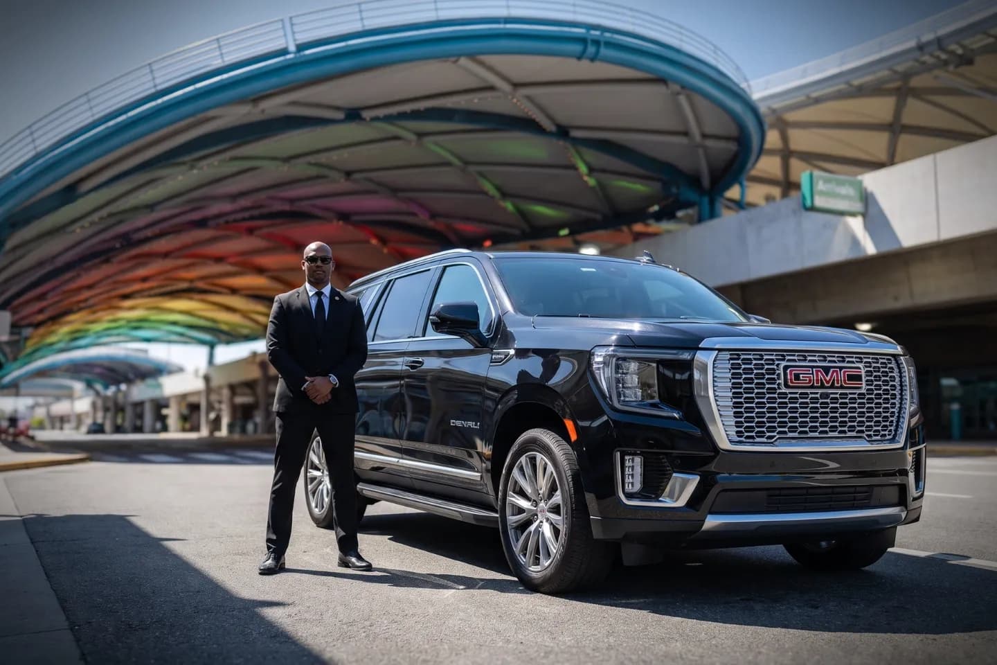 Chauffeur driven black sedan parked outside Frederick Douglass Rochester Airport terminal