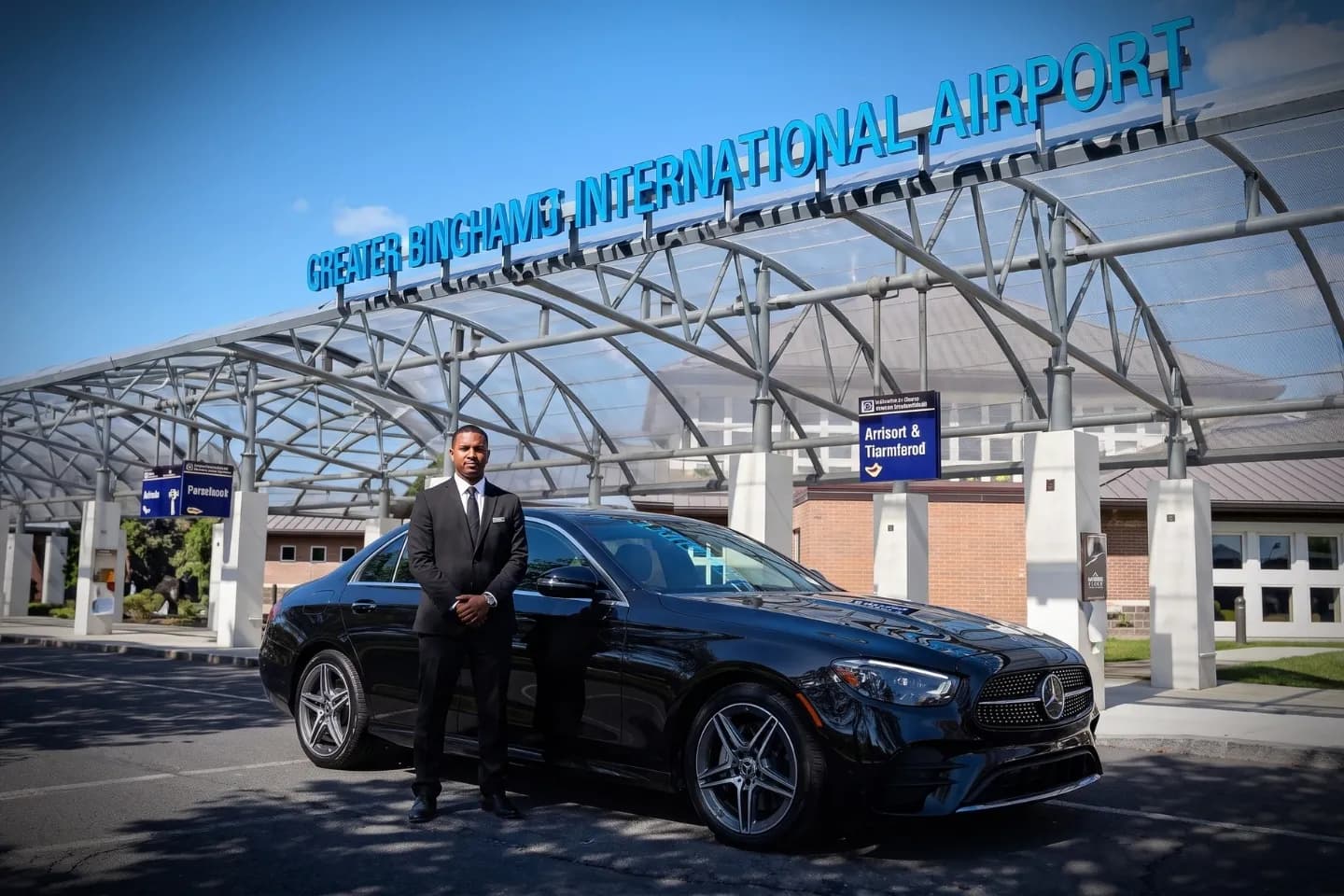 Chauffeured black sedan parked outside Ithaca Tompkins International Airport terminal