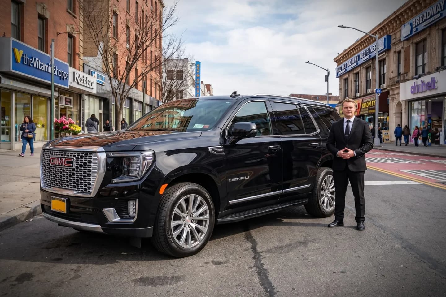 Suited chauffeur opening an executive black sedan door near Fort George, NY