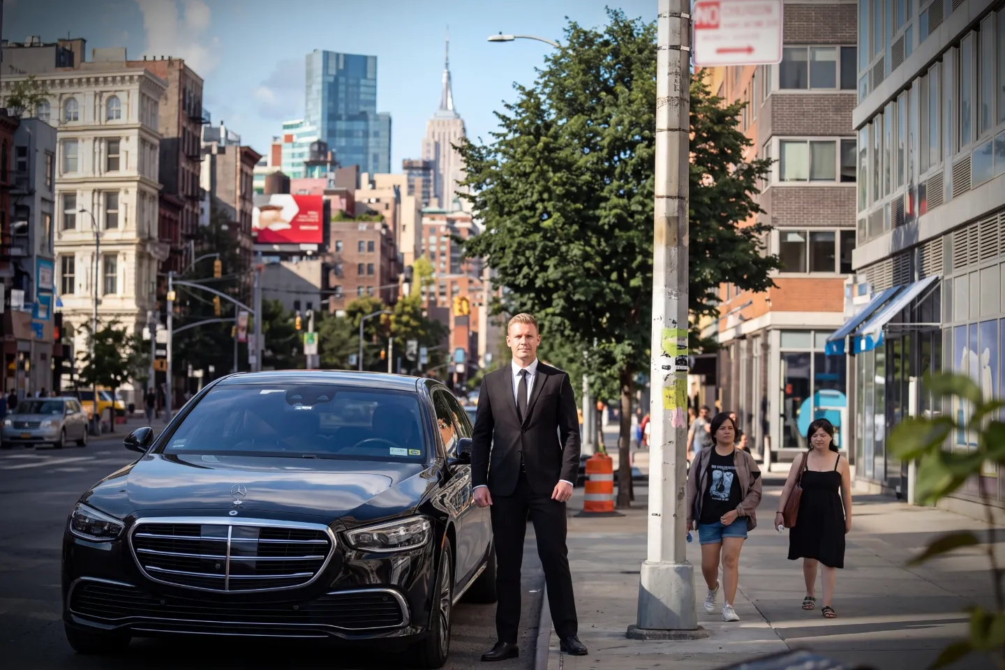 Car Service near Bowery, NY Suited chauffeur opening an executive black sedan door near Bowery, NY