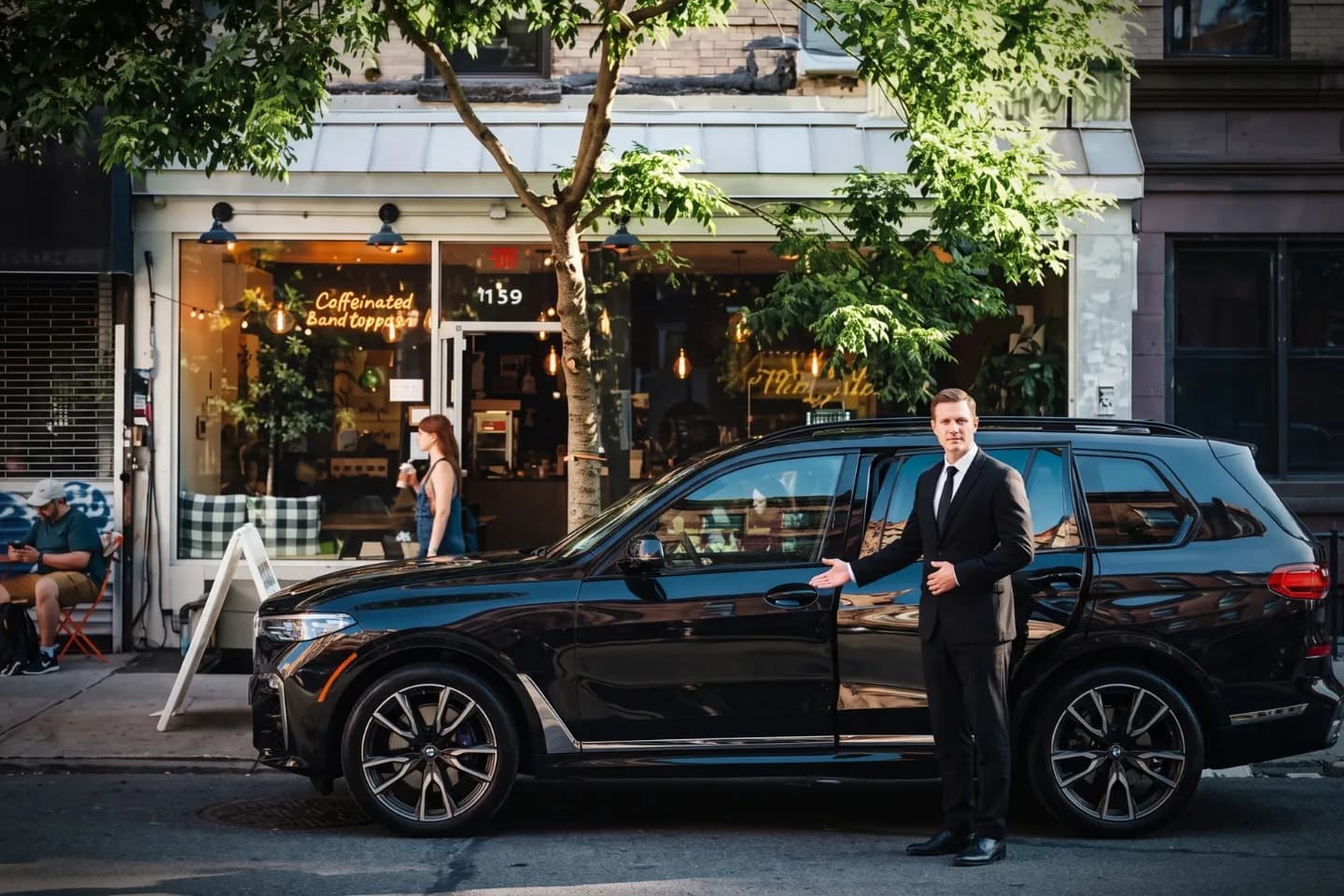 Car Service near East Village, NY Suited chauffeur opening an executive black sedan door near East Village, NY